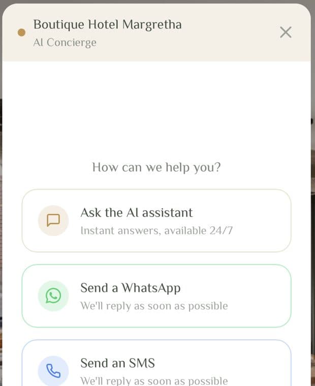 De chatwidget van Lobbiq geopend op de eigen website van een hotel, met drie routes: vraag het de AI-assistent, stuur een WhatsApp, stuur een sms.